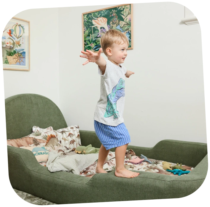 Toddler balancing on green upholstered kids bed