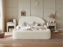 White bed with decorative pillows in a bedroom setting with side tables and decor items.