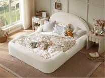 Children's room with a white bed, polka dot blanket, and toys near a window.